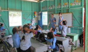 Two nursing students in scrubs teaching young children in a classroom